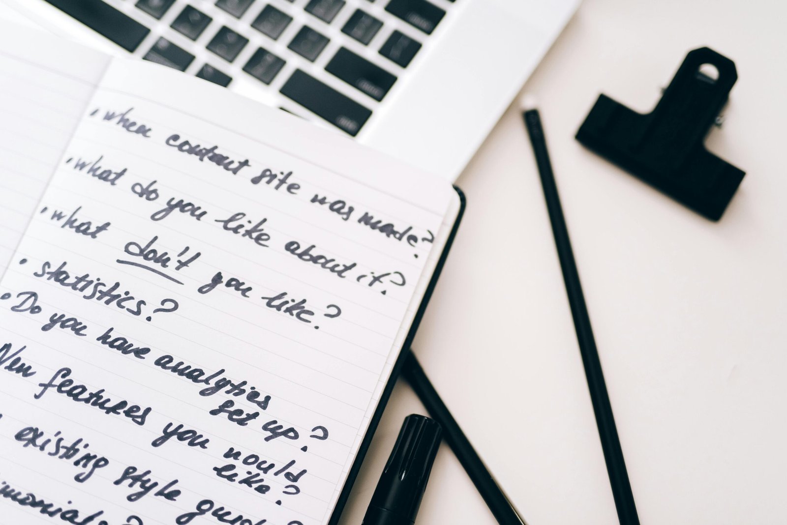 Open notebook with handwritten planning notes beside a silver laptop for website copy planning