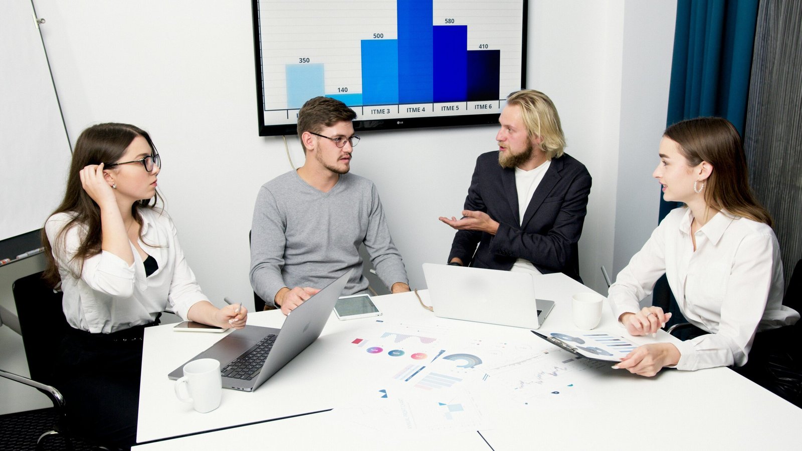 Business team reviewing charts and laptops during a website content audit meeting